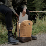 Man enclosing laptop inside the Eden - Tan waxed canvas and reclaimed leather backpack