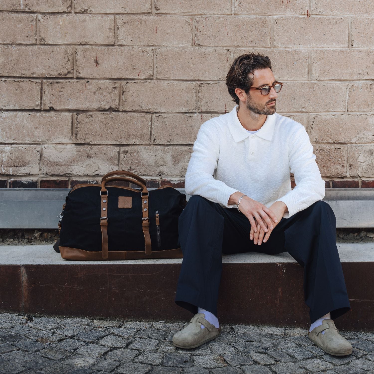 Man sat on outdoor seating with the Humber waxed canvas holdall next to him.
