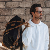 Humber waxed cotton canvas holdall being held over a mans shoulder with the two leather carry handles