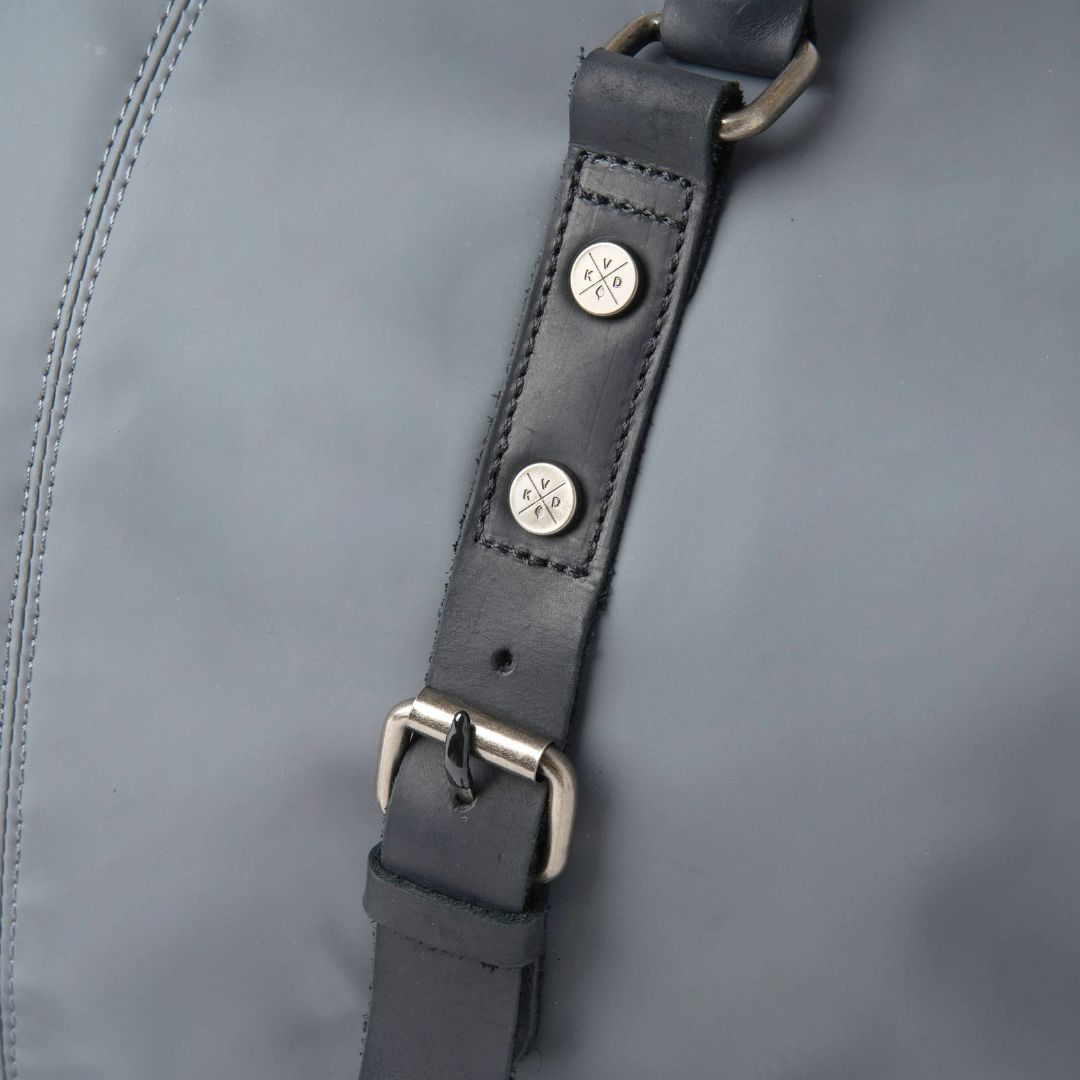 Close-up of a gray leather strap with metal buckles on a gray background