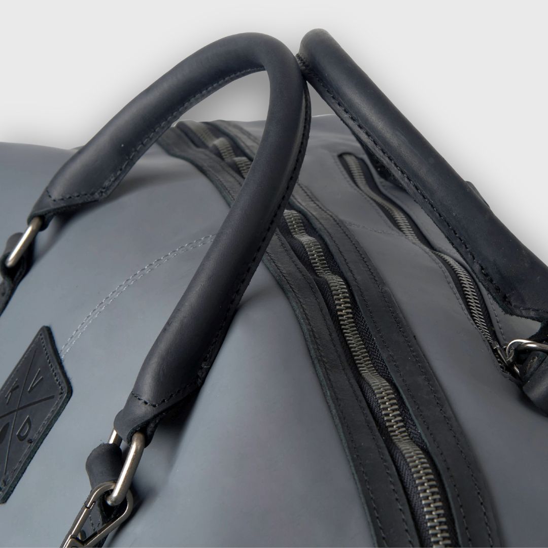 Gray bag with black handle and zipper on a light gray background