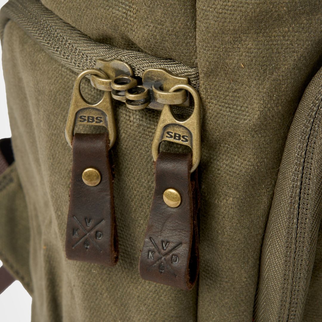 Close up image of interlocking metal zips and branded leather Kovered zip pulls on the Roe backpack