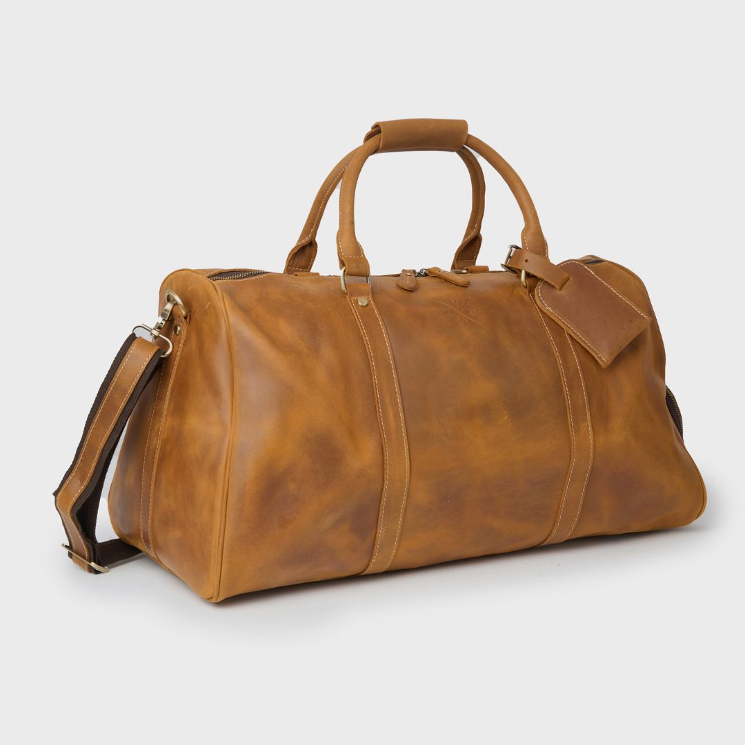 Tan leather duffle bag with shoulder strap and leather tag