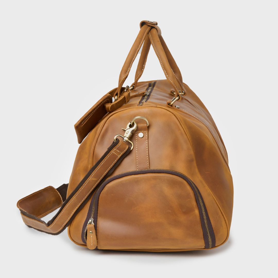 Side view of the Winster leather holdall with shoulder strap and zipped shoe compartment