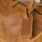 Close up of tan leather holdall luggage tag