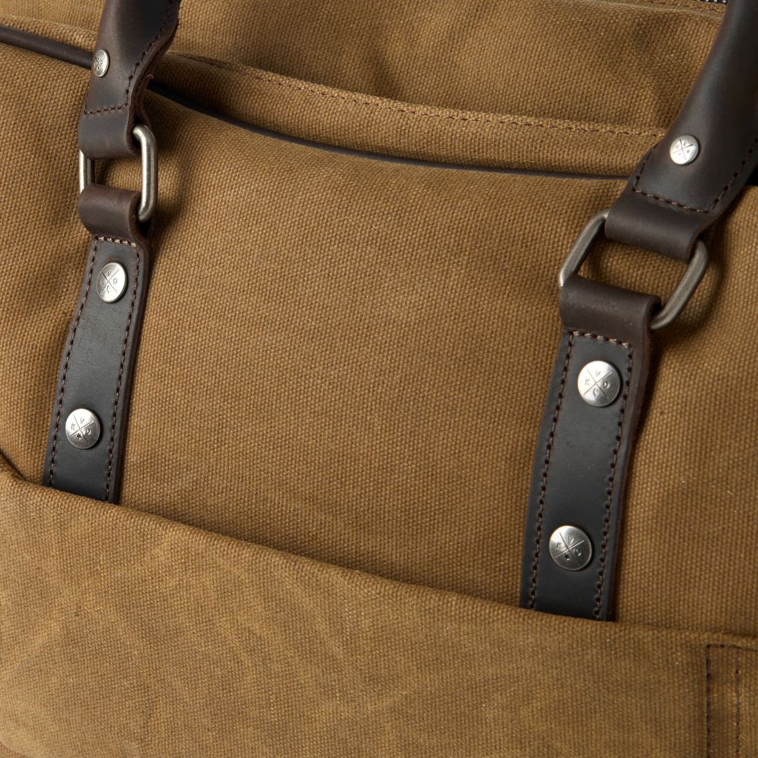 Close-up of a brown bag with leather straps and metal buckles.