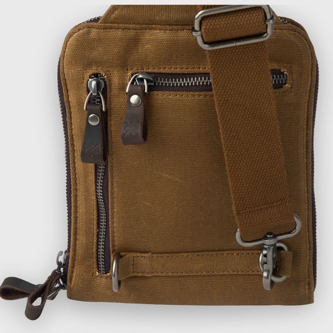 Brown leather bag with zippers and a strap on a white background