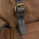 Dark leather and brass magnetic buckle on the Lune Backpack.