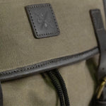 Close up image of dark leather trim and Kovered logo on the Moss Green backpack.