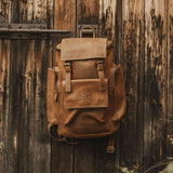 Reclaimed Esk brown leather backpack with multiple pockets hanging on door hook