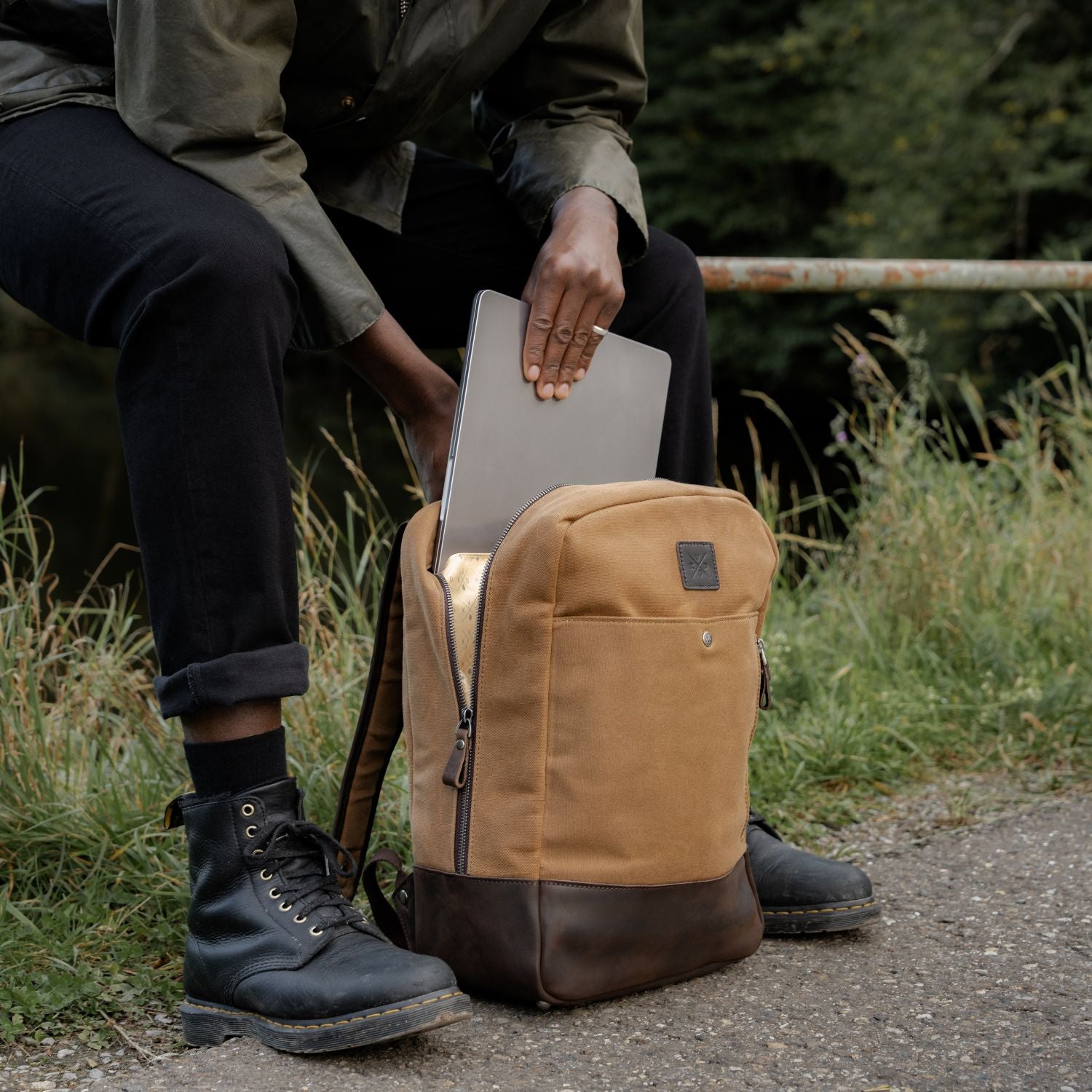 Man enclosing laptop inside the Eden - Tan waxed canvas and reclaimed leather backpack 