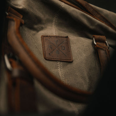 Kovered Humber holdall moss green in waxed canvas and reclaimed leather close up of logo#colour_moss-green
