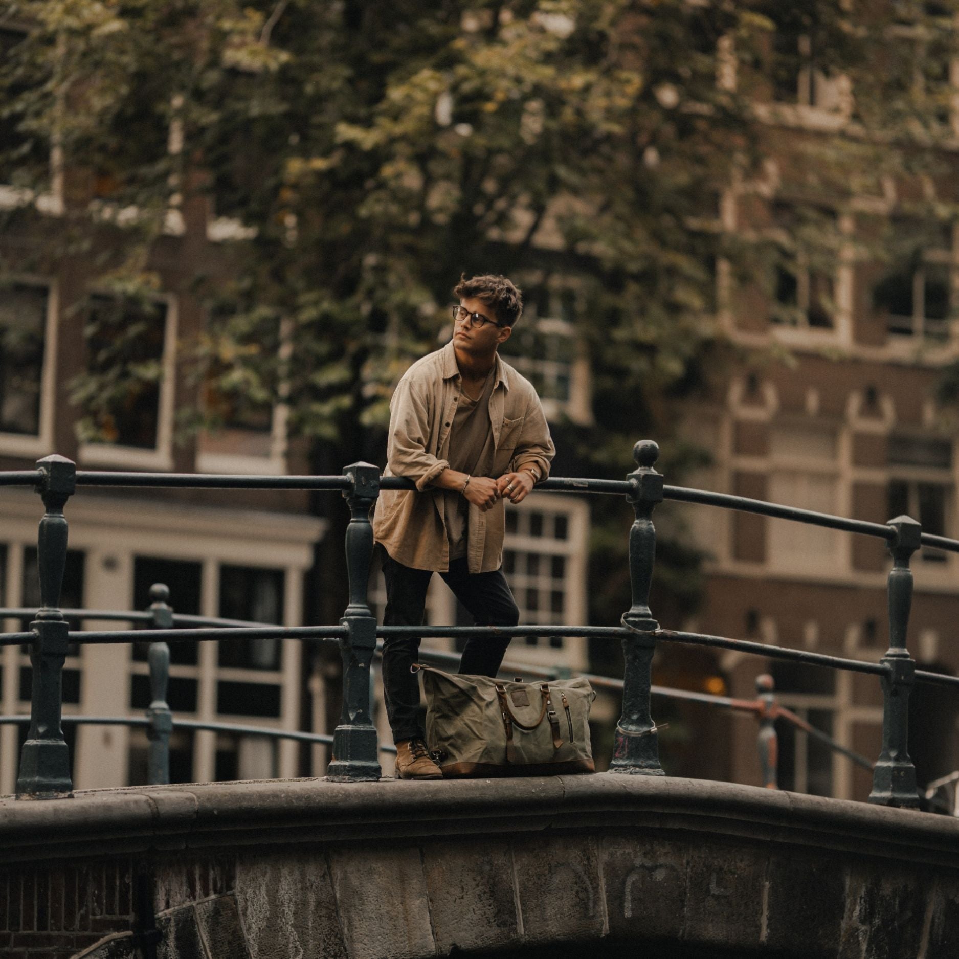 Kovered Humber moss green duffle bag in Amsterdam on a bridge next to model#colour_moss-green