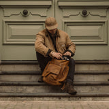 Man sat on steps with vintage leather Esk backpack in tan 