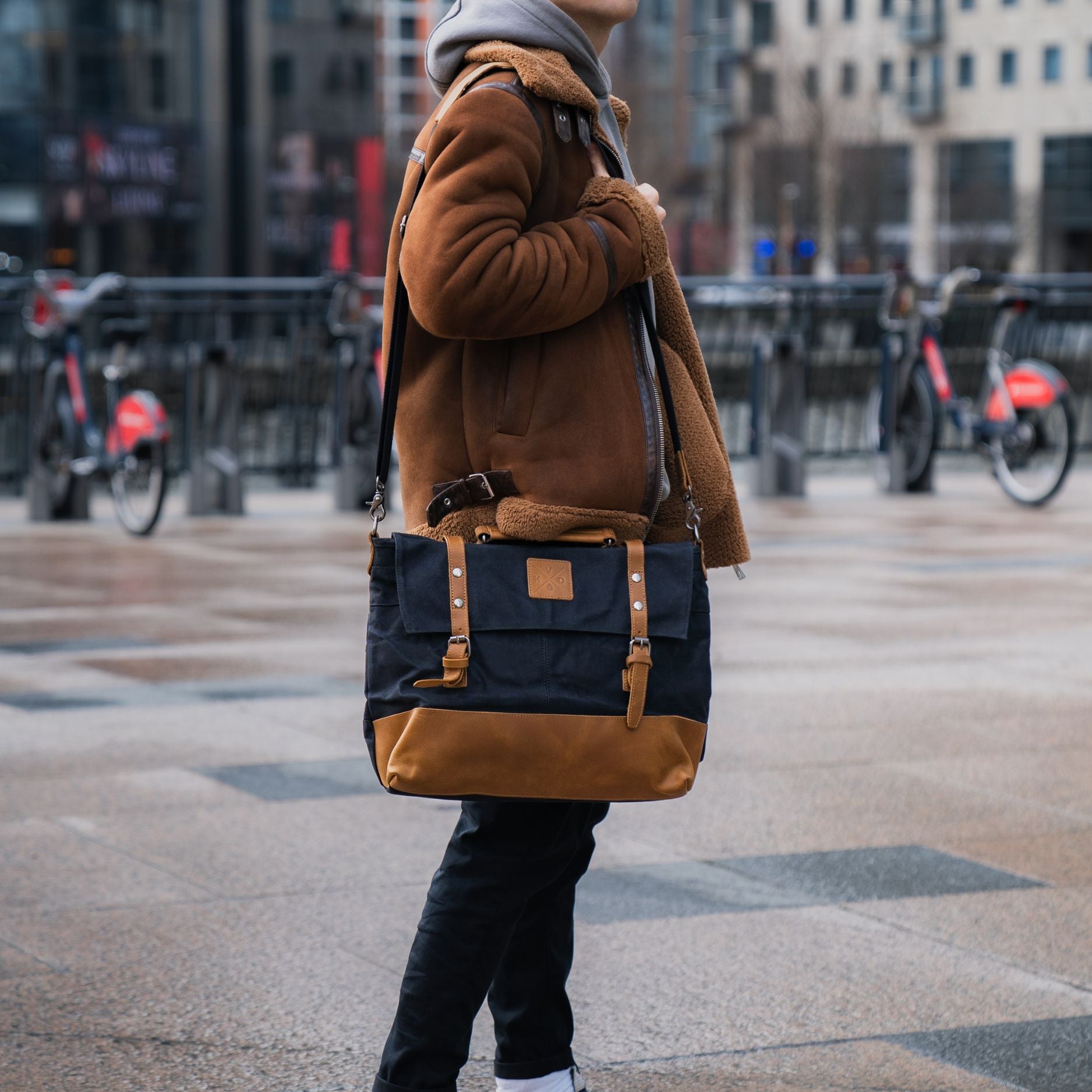 Kovered Mersey black and tan messenger style satchel on models shoulder#colour_black