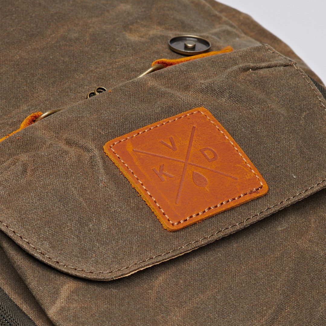 Kovered Roe adventure backpack made from waxed canvas and reclaimed leather close up of KVD logo#colour_moss-green