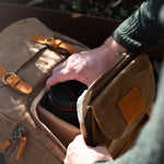 Kovered brown Roe camera backpack close up of man taking camera out of the front pocket#colour_tan