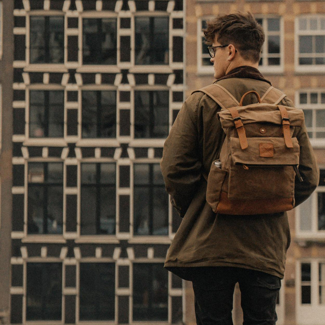 Taw tan rolltop waxed canvas backpack on a model in Amsterdam#colour_tan