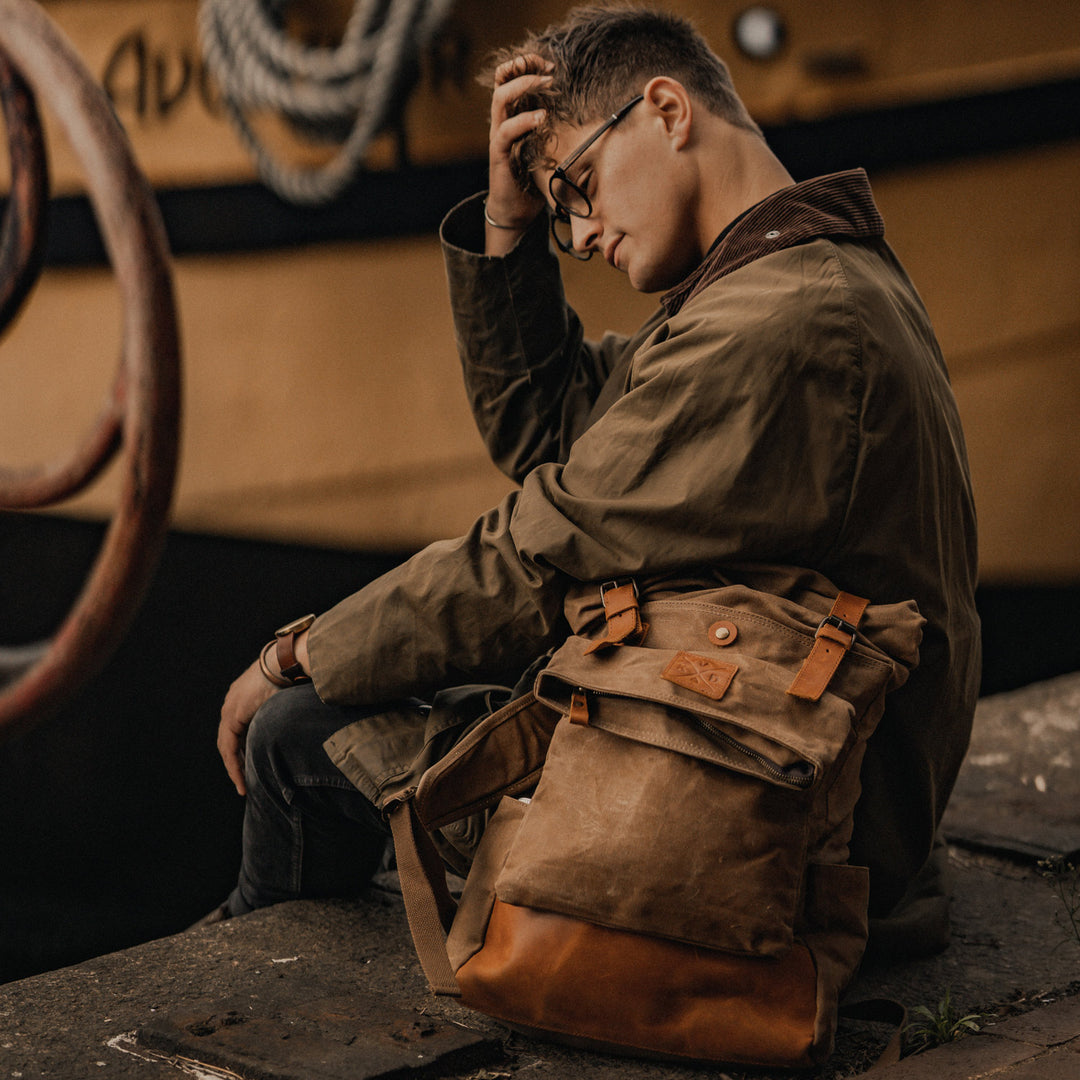 Taw tan waxed canvas rolltop backpack brown next to model#colour_tan