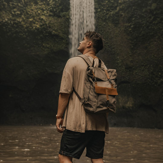 Tay canvas and reclaimed leather backpack on model in front of waterfall in Bali#colour_taupe