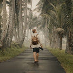 Witham tan canvas and reclaimed leather backpack on man walking in Bali with a camera#colour_tan