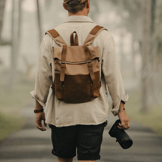 Witham tan canvas and reclaimed leather backpack on man walking in Bali with a camera#colour_tan