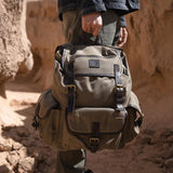 Man holding the Lune Backpack with the top leather carry handle strap