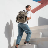 Man climbing steps carrying the Lune canvas backpack in moss green.