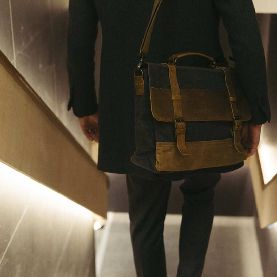 Medway navy messenger bag being carried by the shoulder strap down some stairs#colour_navy
