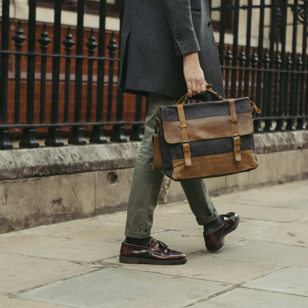 Medway messenger bag navy being carried by the top handle by a male model#colour_navy