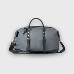 Gray duffel bag with black straps on a light gray background