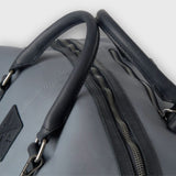 Gray bag with black handle and zipper on a light gray background
