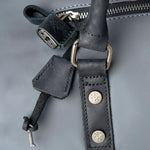 Close-up of a dark gray leather strap with metal hardware on a gray background
