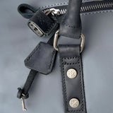 Close-up of a dark gray leather strap with metal hardware on a gray background