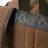 Dark leather trim securely stitched to hold the carry handle and backpack straps on the Lune backpack