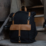 Tay - Black canvas college rolltop backpack placed on wooden steps.