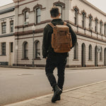 Man in the street wearing the reclaimed vintage leather backpack in tan.