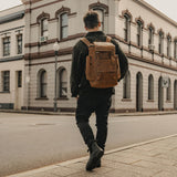 Man in the street wearing the reclaimed vintage leather backpack in tan.