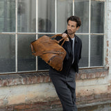 Man holding the tan leather duffel bag