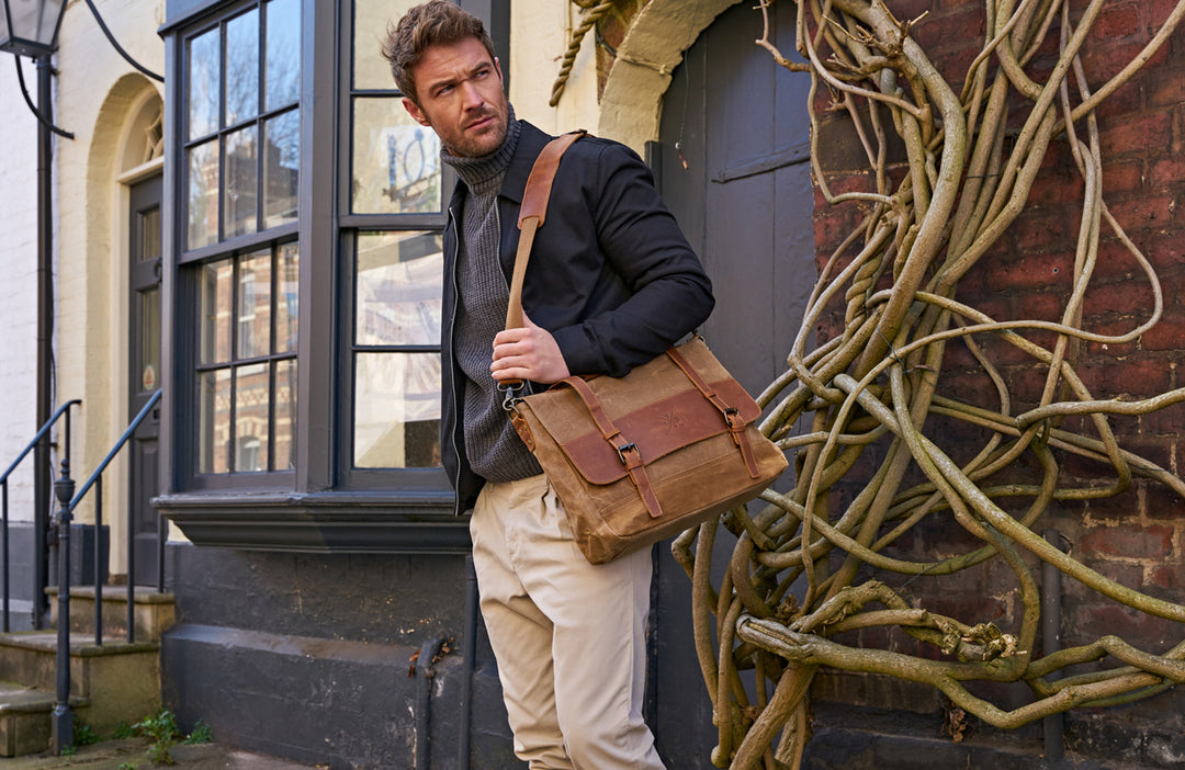 man standing with his kovered waxed canvas messanger satchel made from reclaimed leather in a tan colour