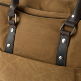 Close-up of a brown bag with leather straps and metal buckles.