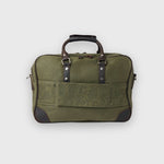 Green travel bag with leather straps on a light gray background