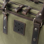 Green bag with leather straps and a brand logo on a green background