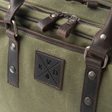 Green bag with leather straps and a brand logo on a green background