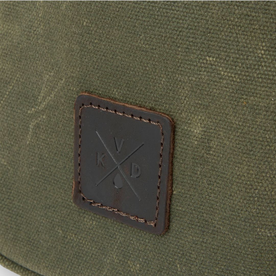 Close-up of a green fabric surface with a brown leather patch featuring a logo.