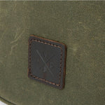 Close-up of a green fabric surface with a brown leather patch featuring a logo.